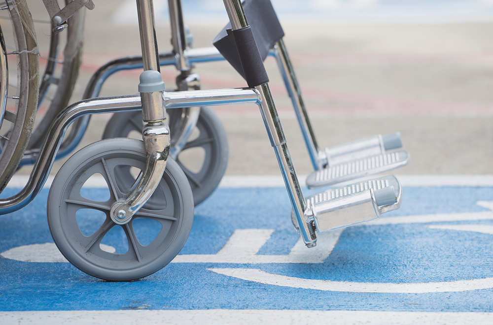 A close up of a wheelchair on top of a blue disabled sign on the ground.