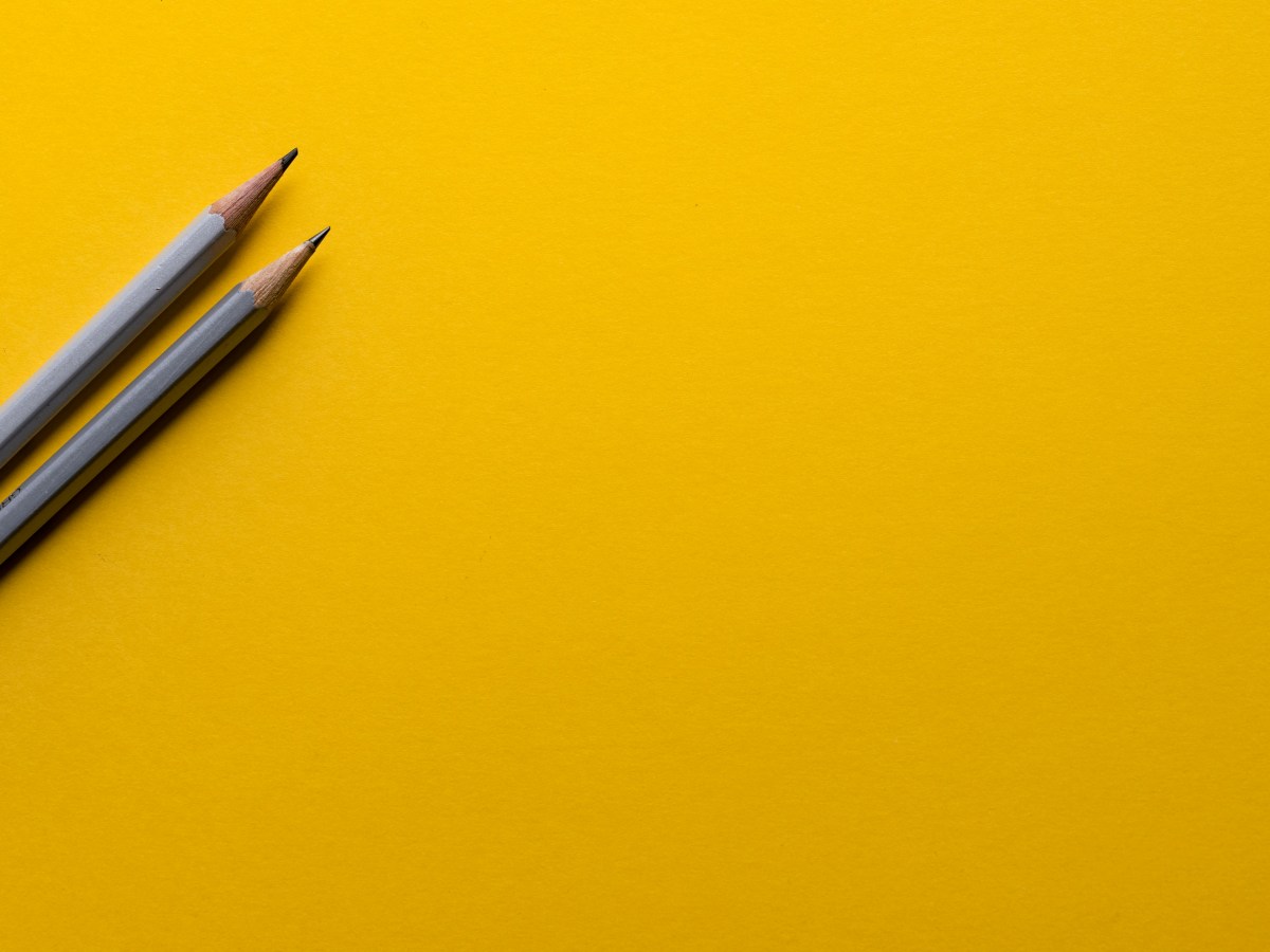 Two grey pencils on a yellow background.