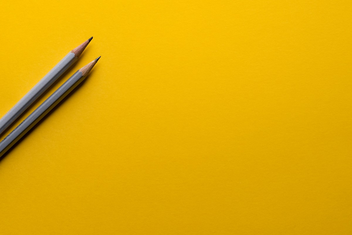 Two grey pencils on a yellow background.