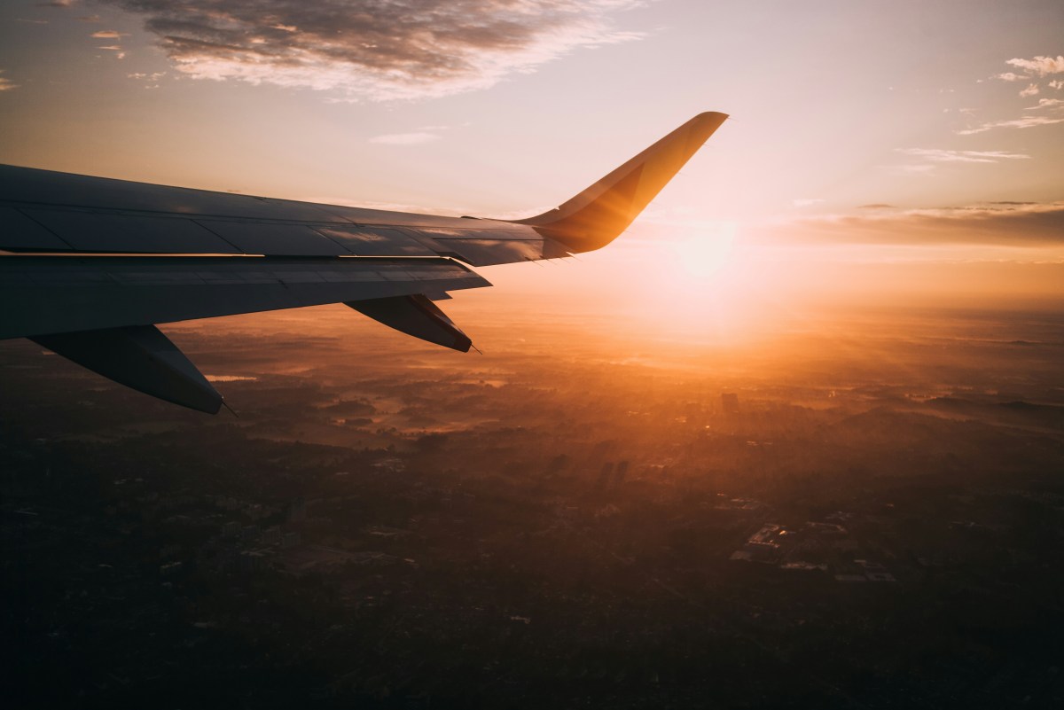 An airplane wing in the sky at sunset.