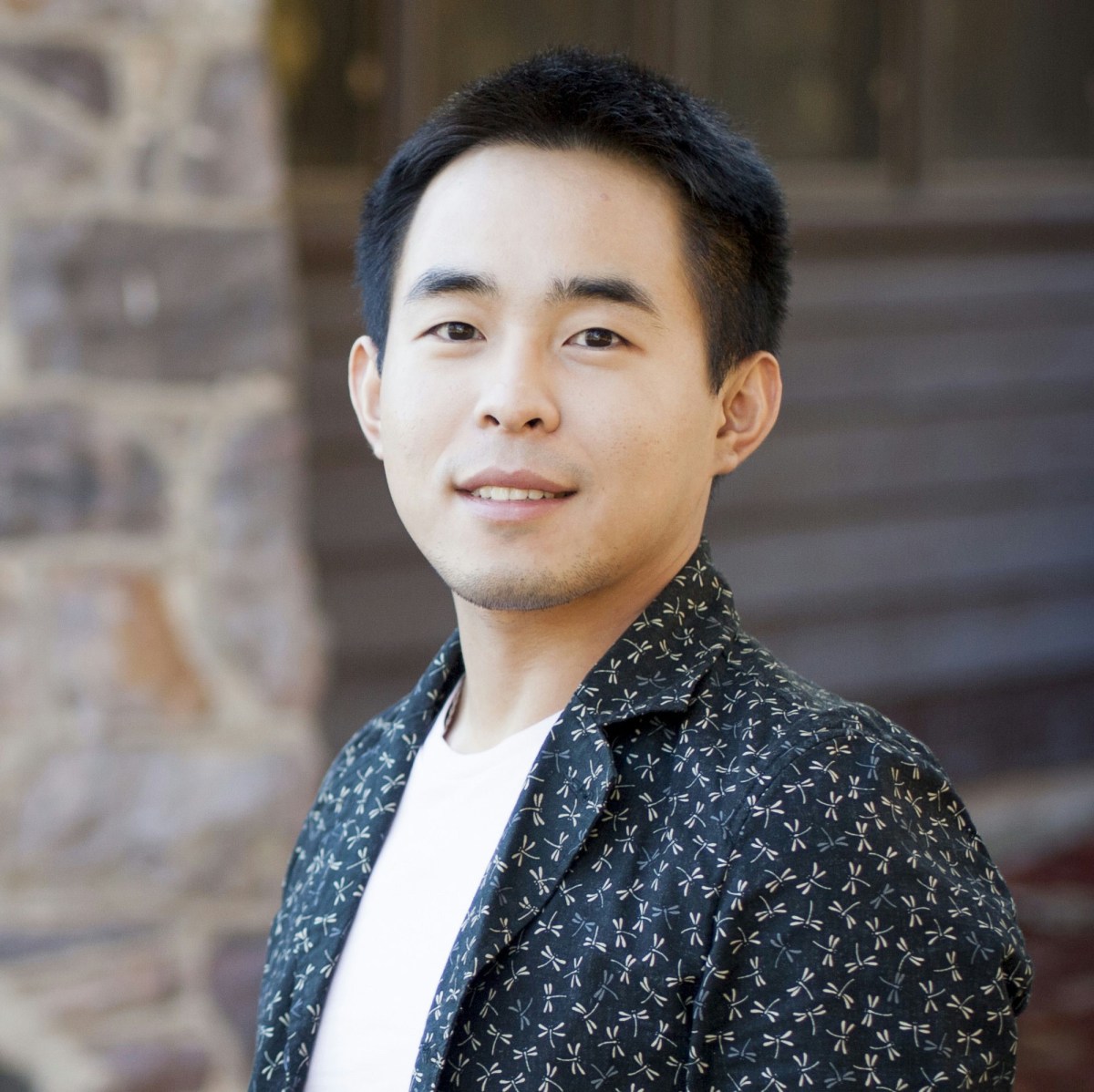 A headshot of Dr Yao Ding, the guest speaker at Something Digital. He is a young looking Asian man with black hair wearing a white tshirt under a patterned dark blue button up shirt.