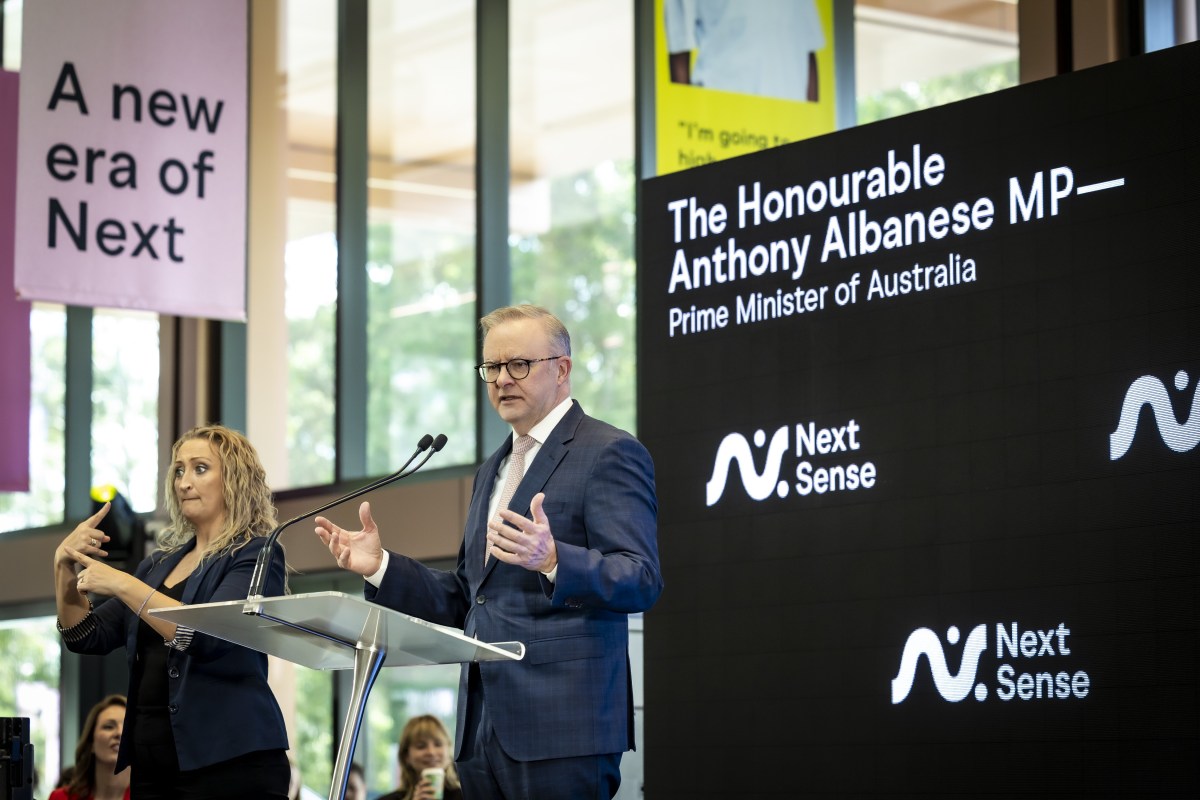 Prime Minister Anthony Albanese, a grey haired man in a suit, stands behind a lectern giving a speech at NextSense.