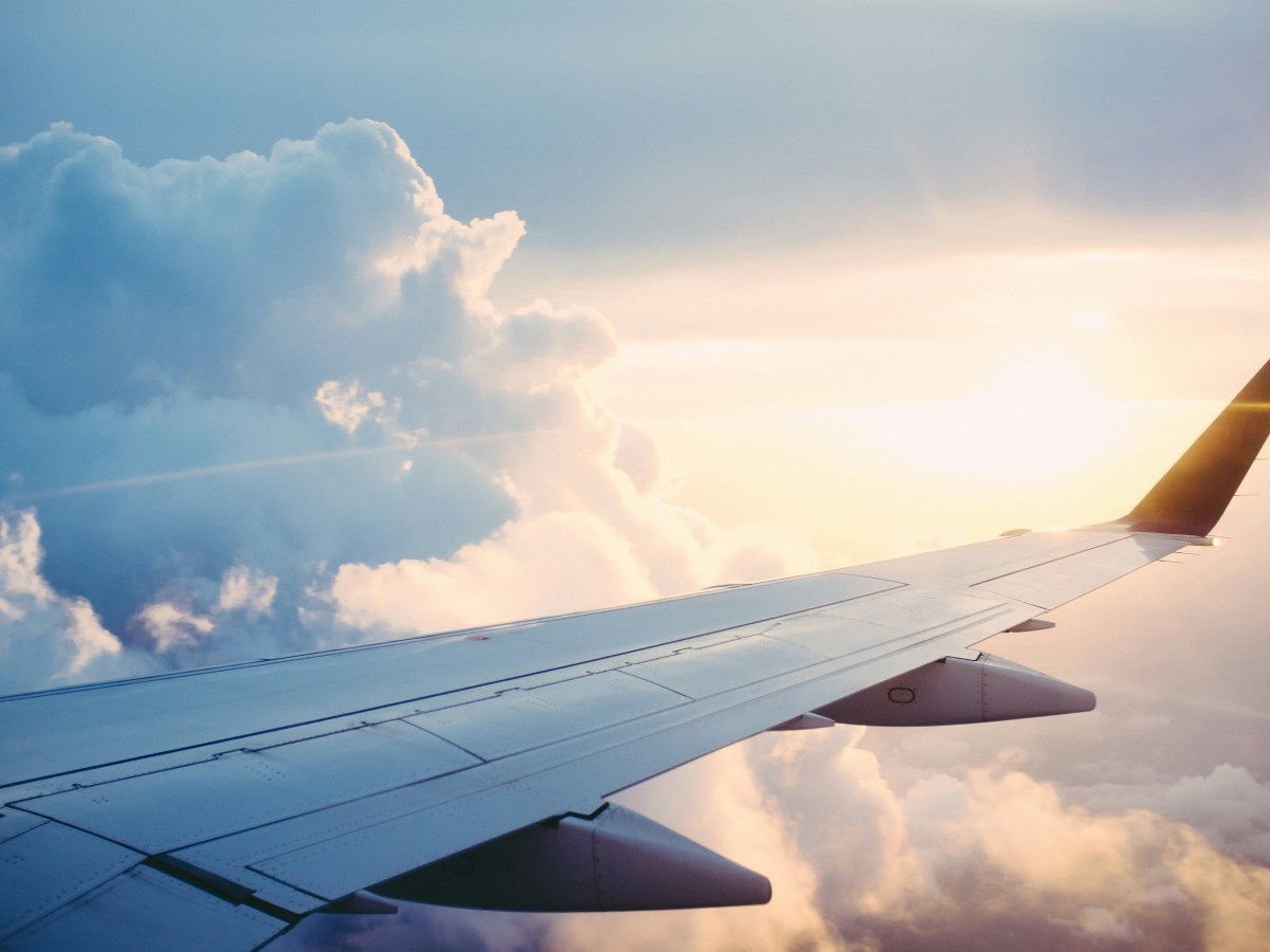 The wing of an airplane amidst sunny clouds.