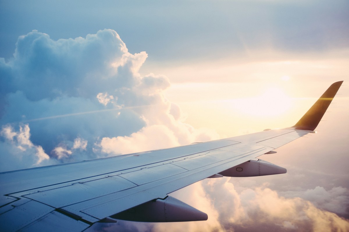 The wing of an airplane amidst sunny clouds.