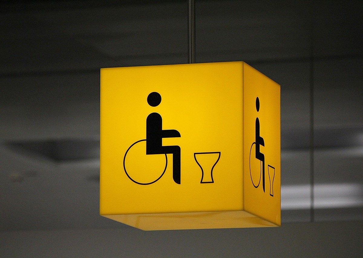 A yellow sign in the shape of a cube, with a wheelchair and toilet icon on it, to represent Changing Places.