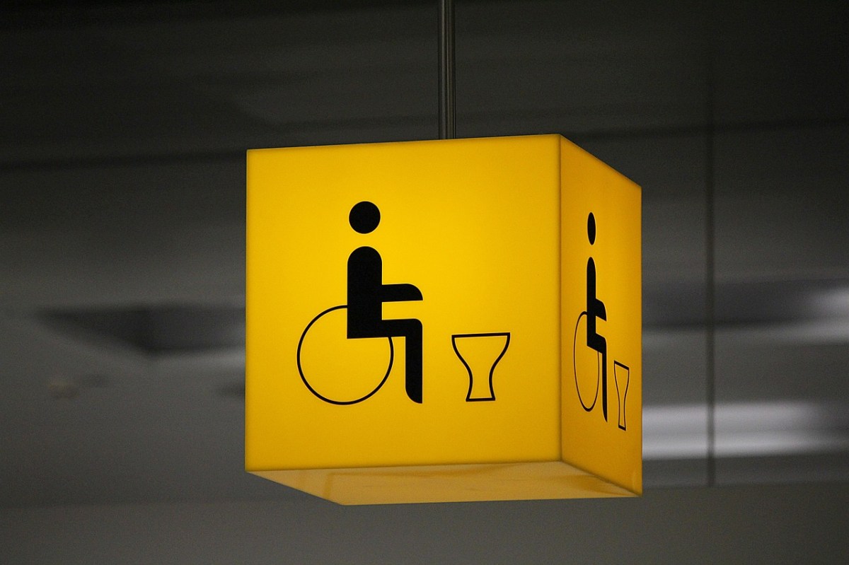 A yellow sign in the shape of a cube, with a wheelchair and toilet icon on it, to represent Changing Places.