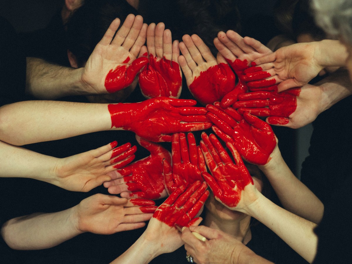 A group of people's hands with red paint on them to represent Foundational Supports.