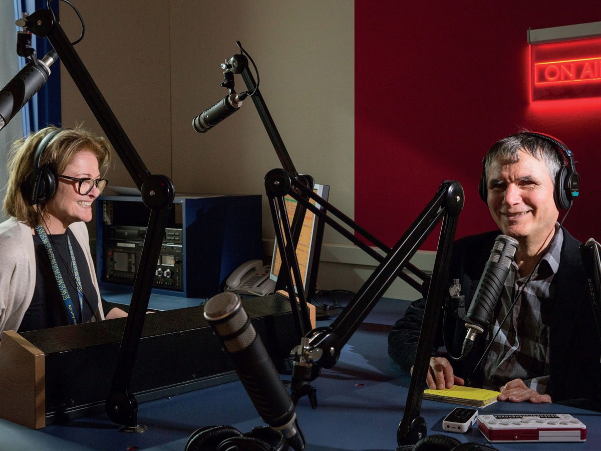 The presenters Peter and Pam from Vision Australia Radio. Pam is on the left in a beige cardigan, and Peter, an elderly man, is on the right. They are surrounded by radio equipment like microphones.