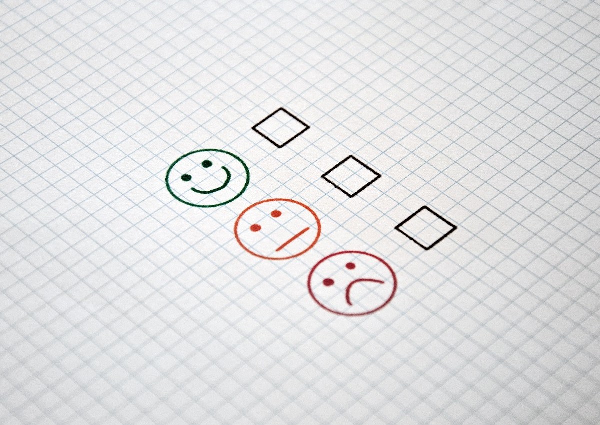 A checklist of three boxes on a piece of paper with a smiley face, neutral face and unhappy face next to the boxes.