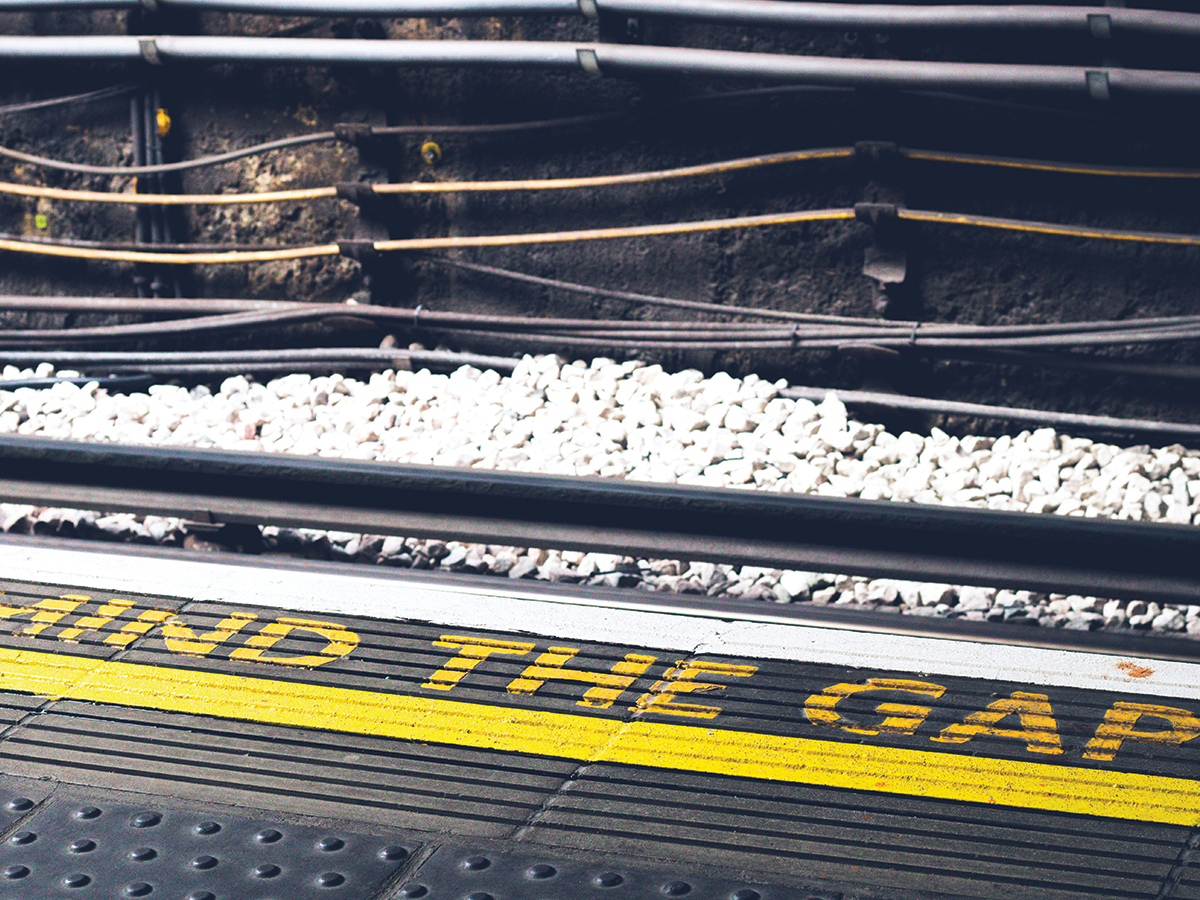 A train line beside a platform which has the words Mind the Gap painted on it in yellow.