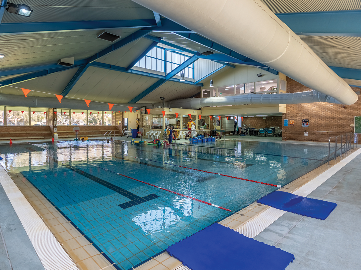 A swimming pool in a wide angle shot, inside a brick building.