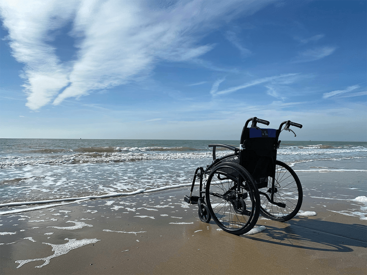 A wheelchair at the beach, facing out into the water.