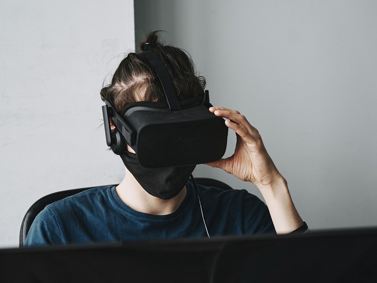 A young person in a plain blue top, wearing a virtual reality mask.