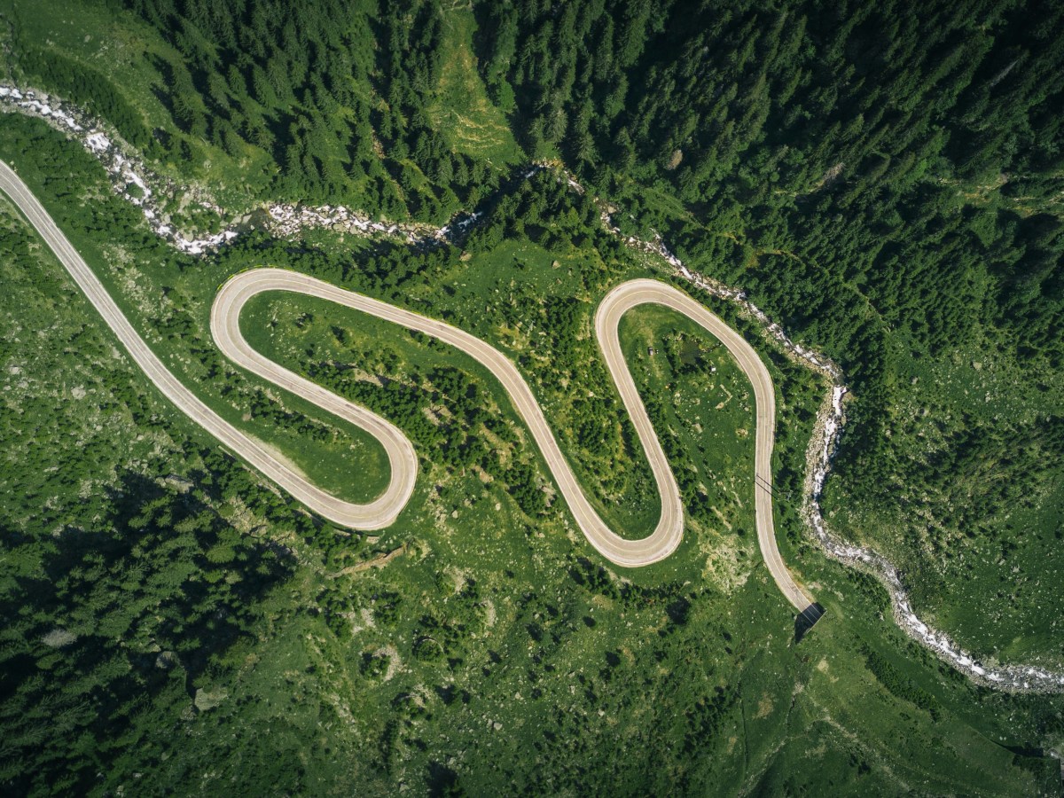 An aerial photo of a road running through a green forest.