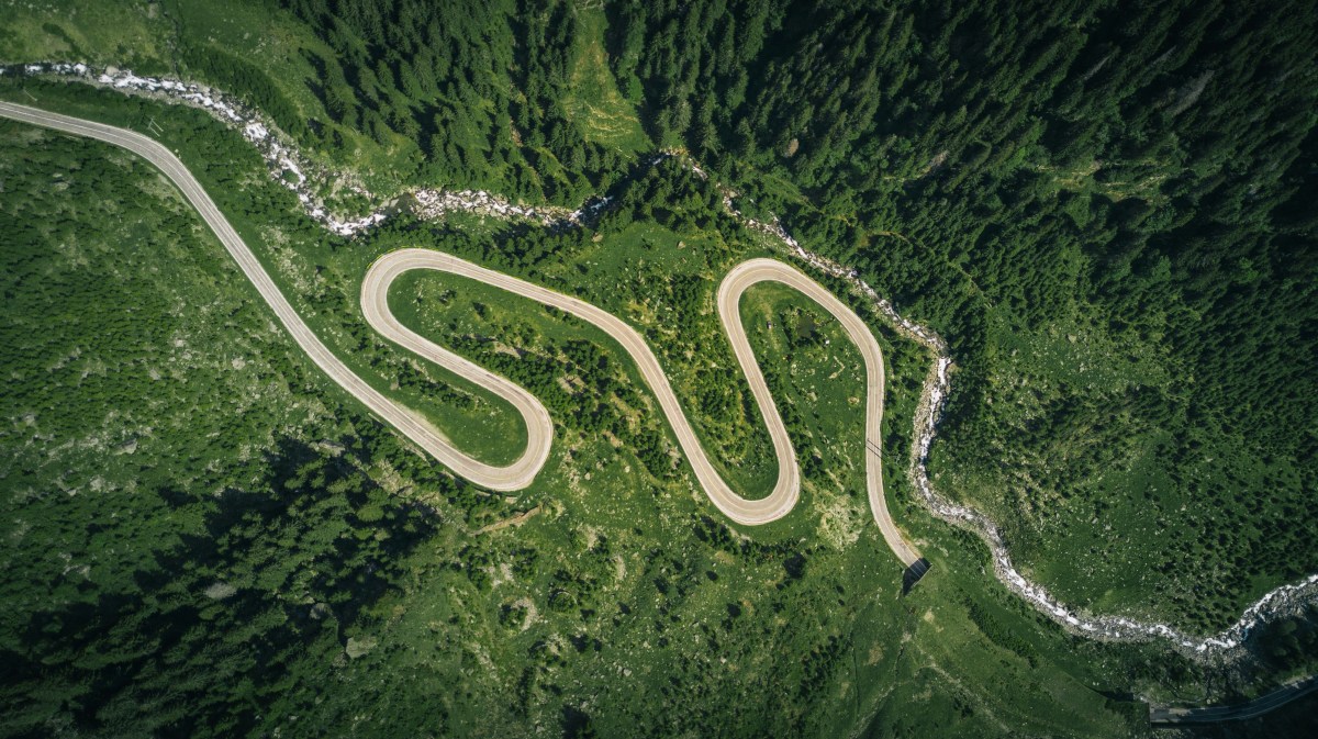 An aerial photo of a road running through a green forest.